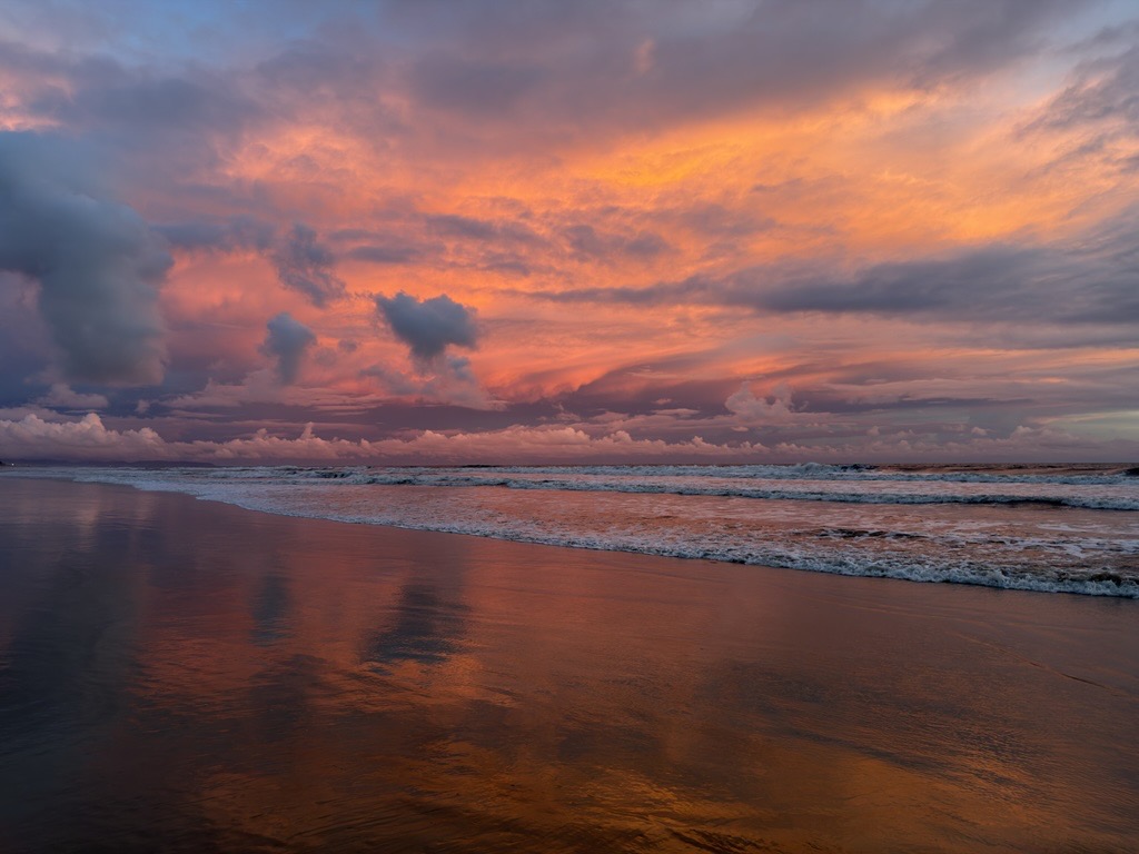 Sunset clouds reflected on a beach